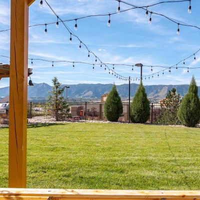 Vistas at Jackson Creek expansive green lawn with string lights and Rocky Mountain backdrop