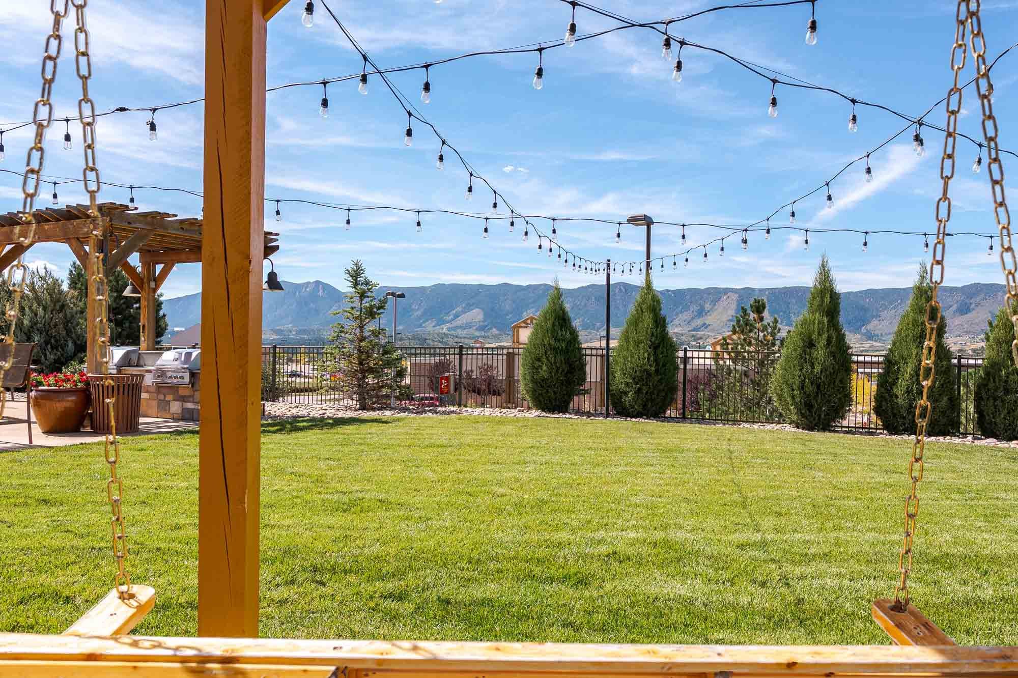 Vistas at Jackson Creek expansive green lawn with string lights and Rocky Mountain backdrop