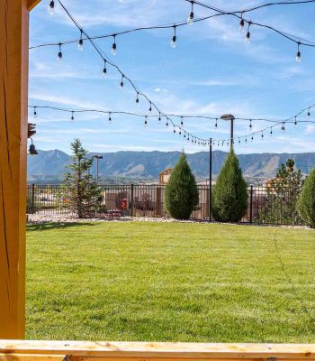 Vistas at Jackson Creek expansive green lawn with string lights and Rocky Mountain backdrop