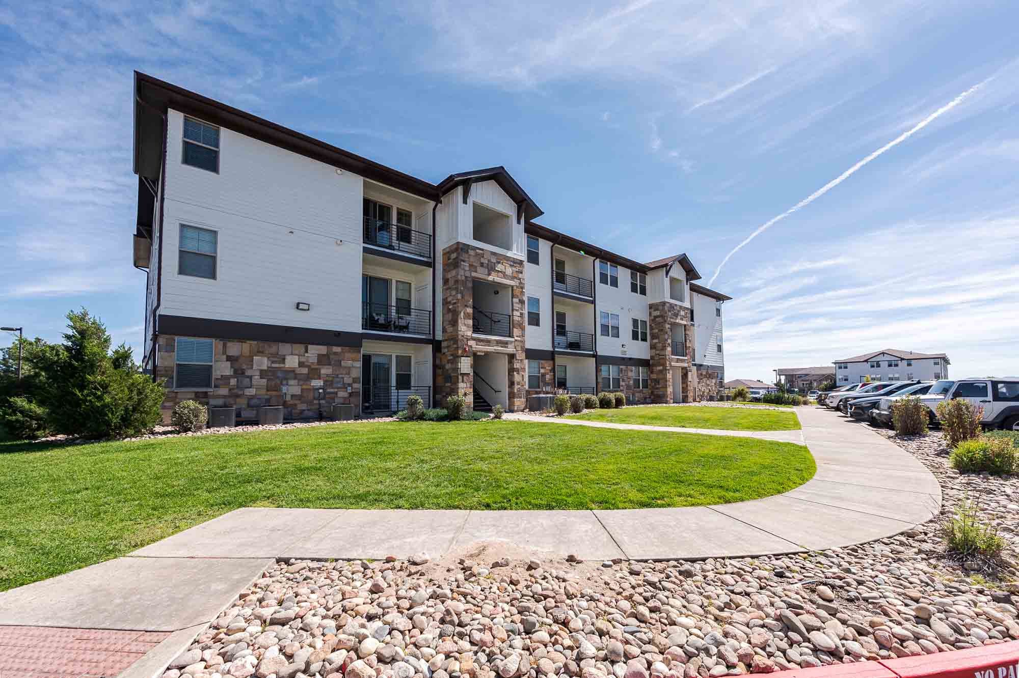 Vistas at Jackson Creek apartment building exterior with stone accents and manicured landscaping