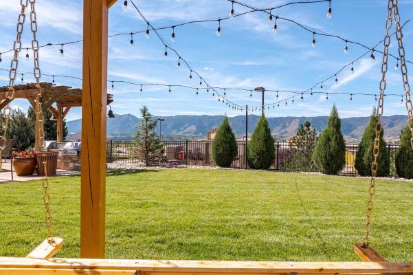 Vistas at Jackson Creek expansive green lawn with string lights and Rocky Mountain backdrop