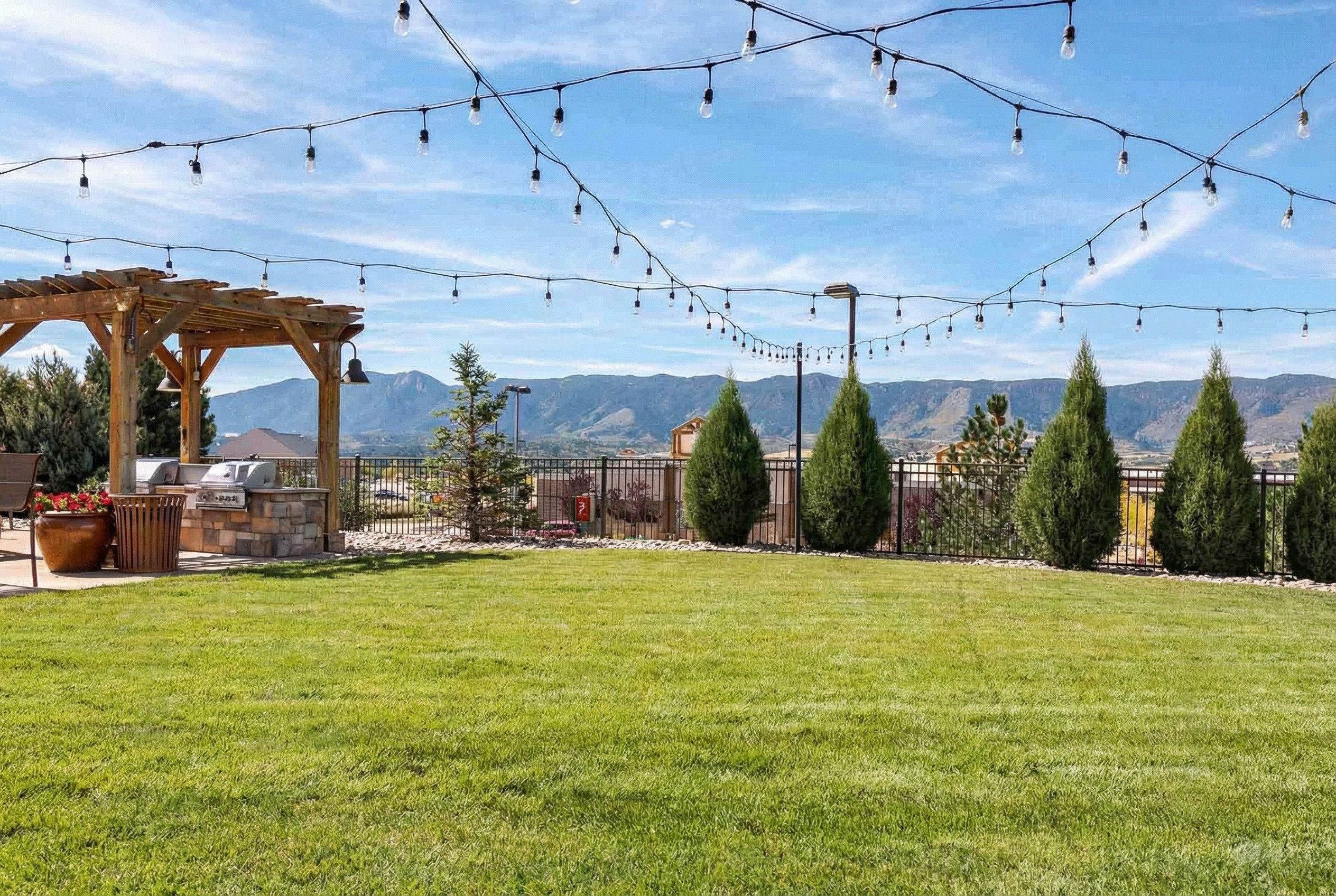 Vistas at Jackson Creek expansive green lawn with string lights and Rocky Mountain backdrop
